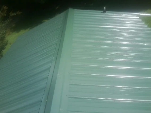 New green metal panels meeting at the ridge of a roof — Flat Roof Repair work by our crew in Blue Diamond