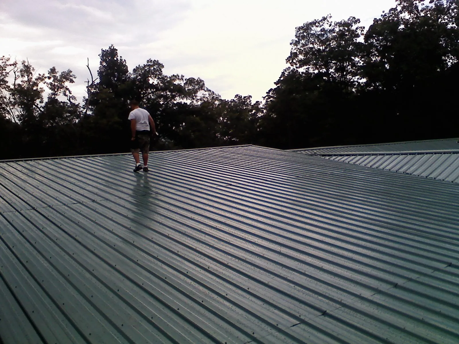 Roofer walking a wide expanse of new green metal roofing in Blue Diamond