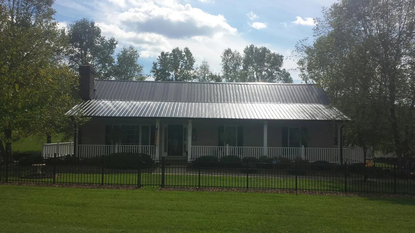 Gray metal roof on a brick ranch with a full width front porch — Gutter Guard Installation work by our crew in Blue Diamond