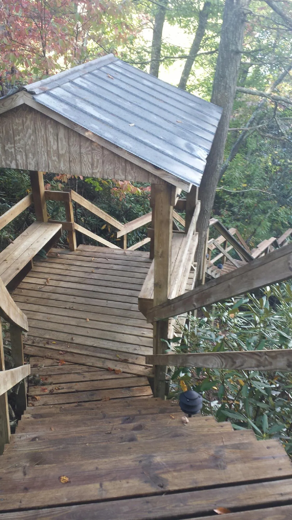 Metal roofed shelter over wooden steps on a wooded walkway — Skylight Repair & Installation work by our crew in Blue Diamond