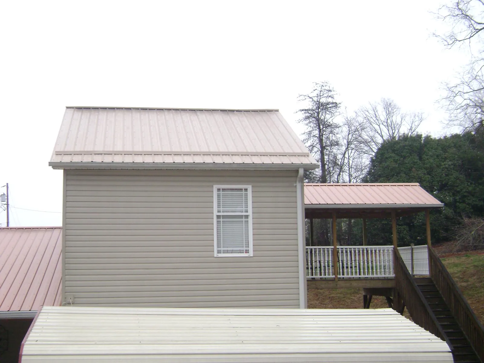 Tan metal roofs on a two story addition and attached porch, from a Roof Replacement job in Blue Diamond