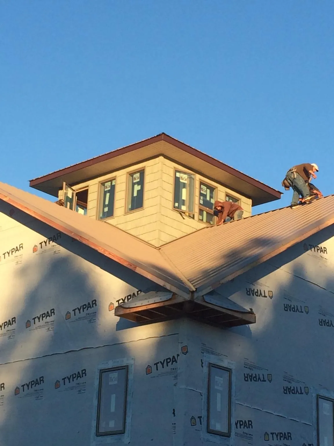 Roofers working around a rooftop cupola on a new metal roof at sunset — Roof Waterproofing in Blue Diamond by Roofing Brothers